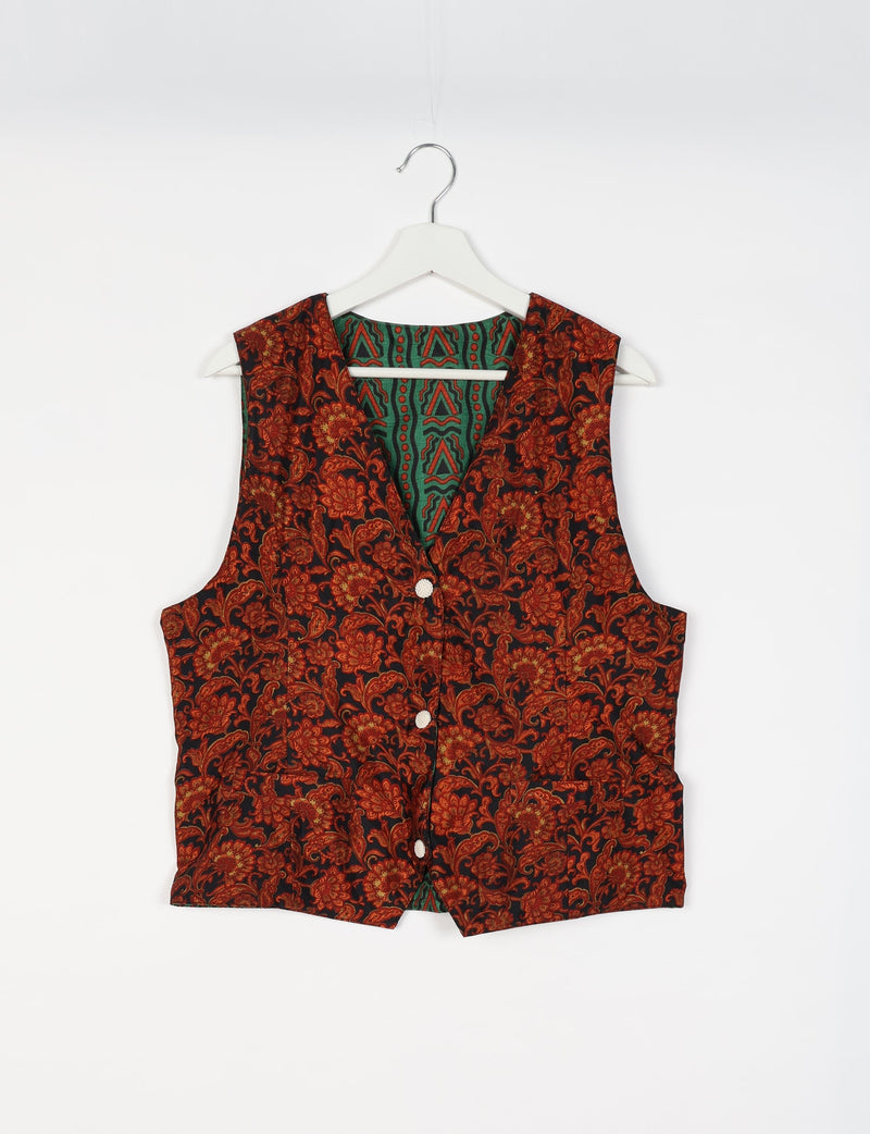 Black waistcoat with red floral tropical pattern, white buttons, and green patterned inner lining, hanging on white hanger