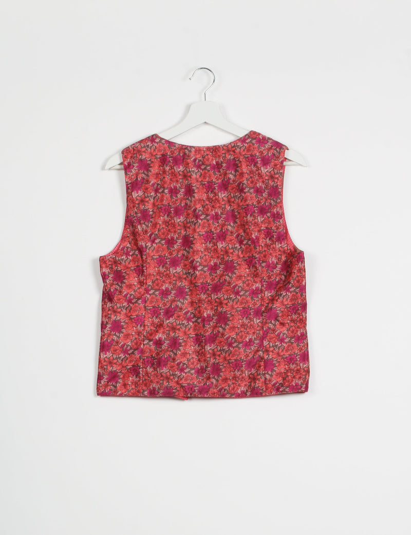 Pink floral sleeveless waistcoat hanging on white hanger, back view, with red and magenta flower pattern on fabric