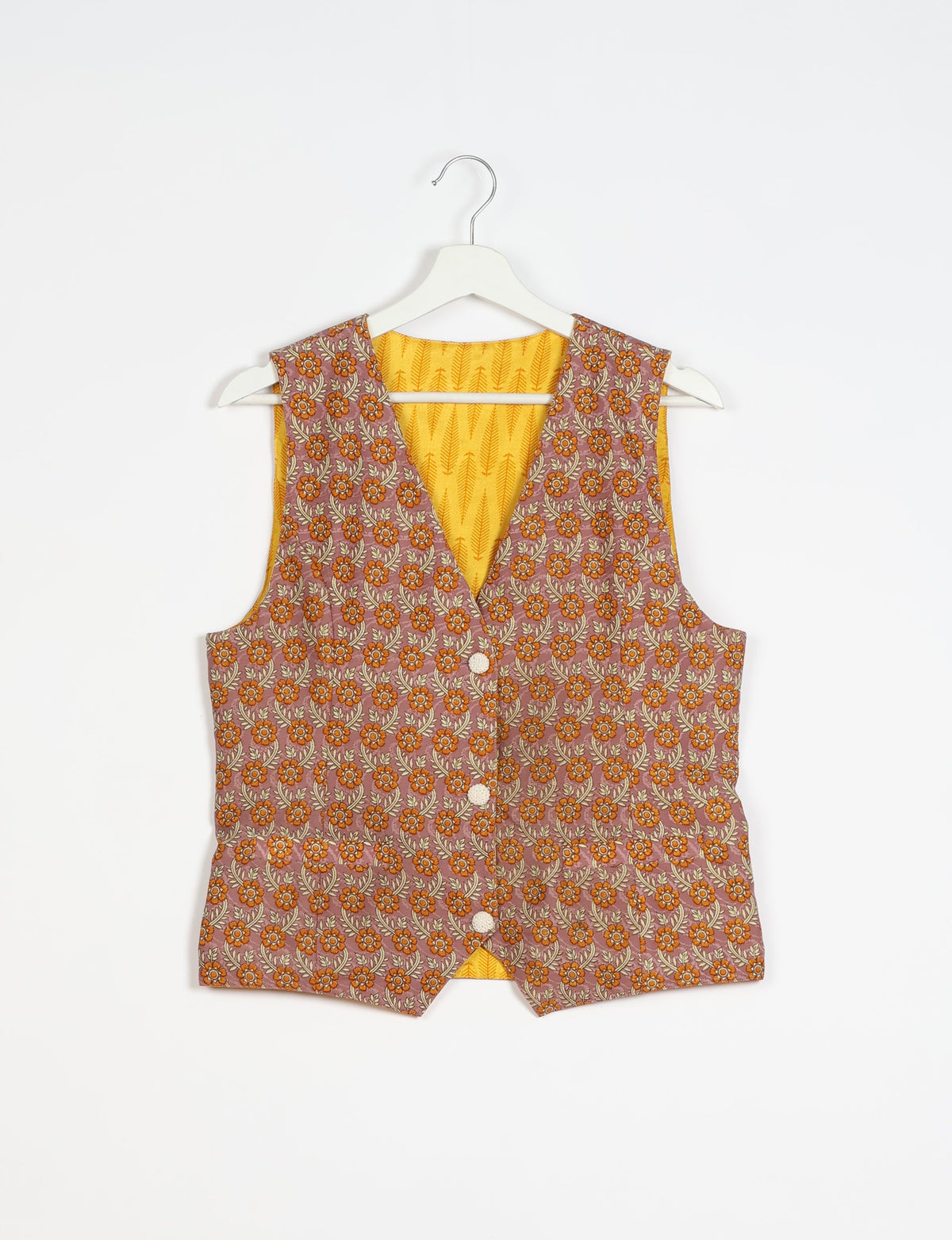 Brown floral patterned sleeveless waistcoat with front buttons and yellow patterned inner lining, hanging on white hanger