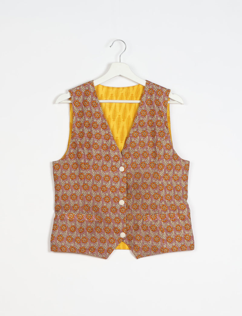 Brown floral patterned sleeveless waistcoat with front buttons and yellow patterned inner lining, hanging on white hanger