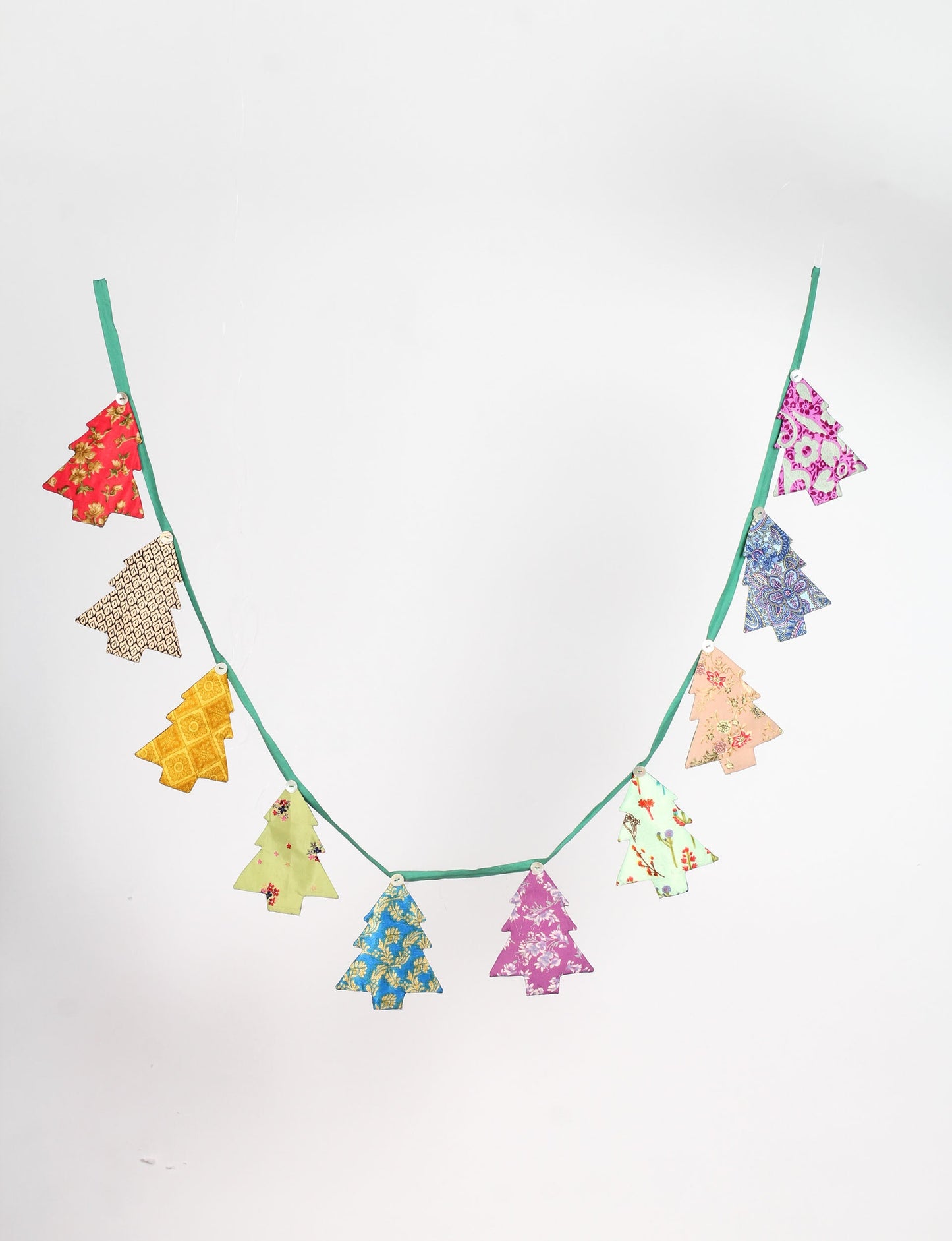 Eco-friendly Christmas bunting featuring Christmas tree patches made from recycled saris, attached to canvas lace with buttons. A sustainable, upcycled decoration promoting circular fashion and ethical holiday decor.