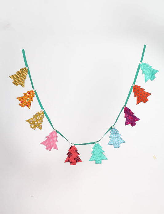 Eco-friendly Christmas bunting featuring Christmas tree patches made from recycled saris, attached to canvas lace with buttons. A sustainable, upcycled decoration promoting circular fashion and ethical holiday decor.