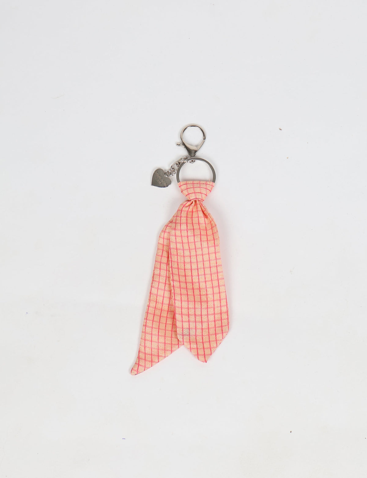 Pink geometric patterned fabric tied as a miniature necktie on a silver keyring with a heart-shaped charm, flat lay
