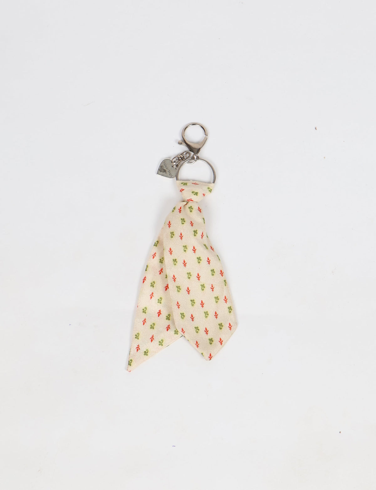 Beige fabric tie keychain with small red and green floral micro design and silver metal clasp with heart charm