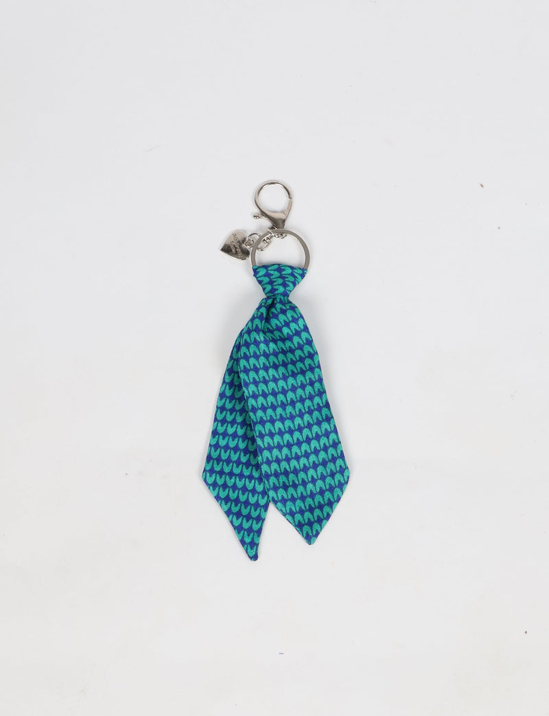 Blue tie keychain with a micro pattern of teal shapes, silver keyring, lobster clasp, and small heart charm attached