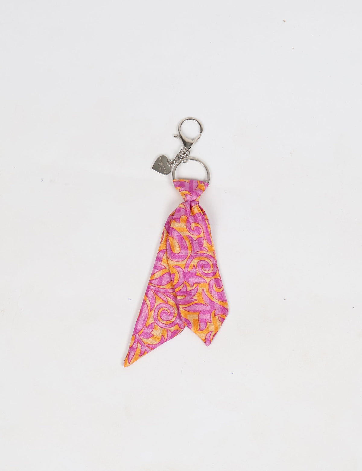 Pink and orange tropical patterned fabric tie keychain with silver ring and heart-shaped charm, flat lay on white background