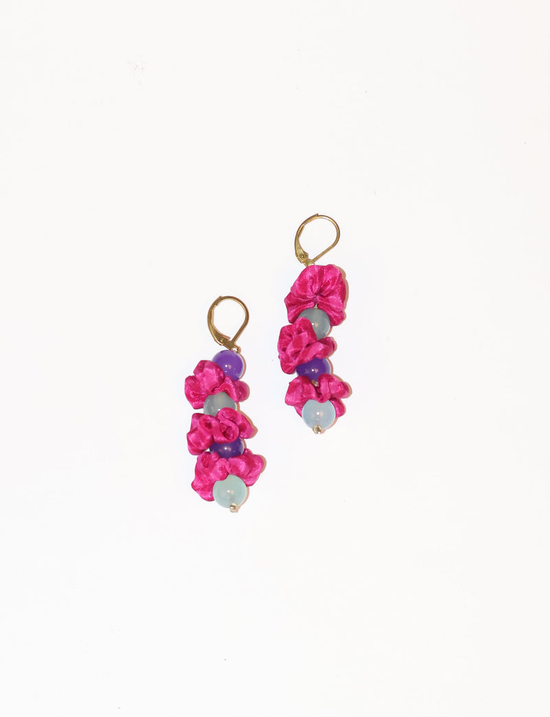 Pair of pink abstract floret dangler earrings with purple and light blue beads and gold-tone hooks on white background