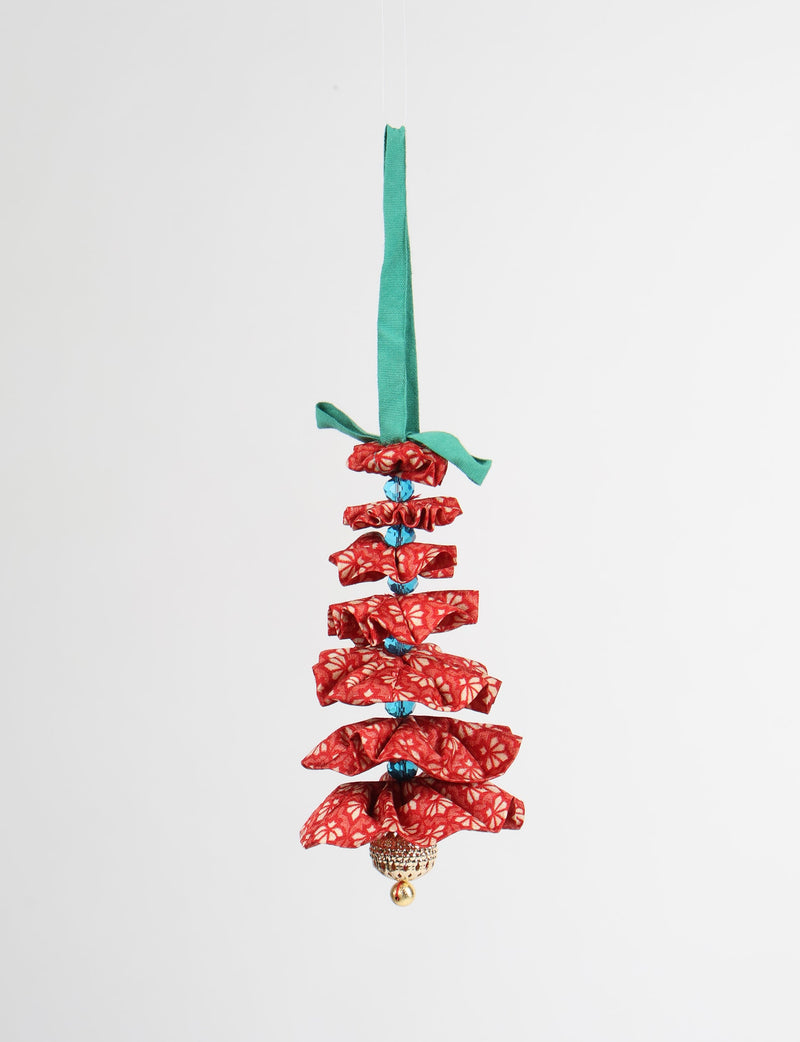 Red fabric Christmas tree ornament with abstract pattern, blue beads, gold bell, and green hanging loop, front view