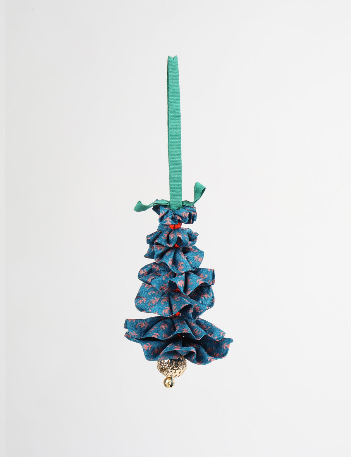 Blue fabric Christmas tree ornament with pink abstract pattern, green hanging loop, and gold textured bell at bottom