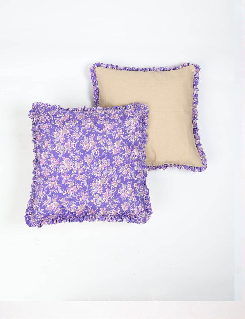 Set of two cushion covers with purple floral frill edges, one with purple floral print and one solid beige back, flat lay
