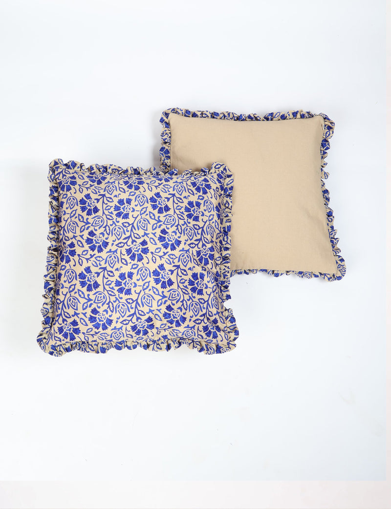 Set of two beige cushion covers with blue tropical floral print and frilled edges, one plain and one patterned, flat lay view
