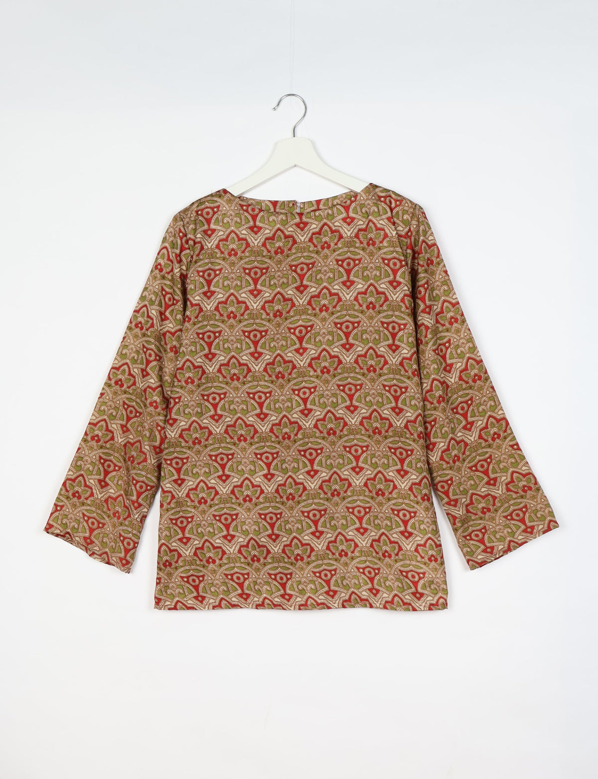 Beige long-sleeve top with red and green tropical floral geometric pattern, round neckline, hanging on white hanger
