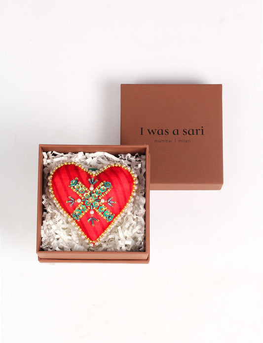 A Christmas heart ornament made from recycled sari fabric, featuring traditional Aari embroidery, representing sustainable, eco-friendly fashion. Handcrafted by artisans, this zero-waste, fair trade product symbolizes recycled material clothing and conscious clothing choices within eco-friendly and circular fashion.