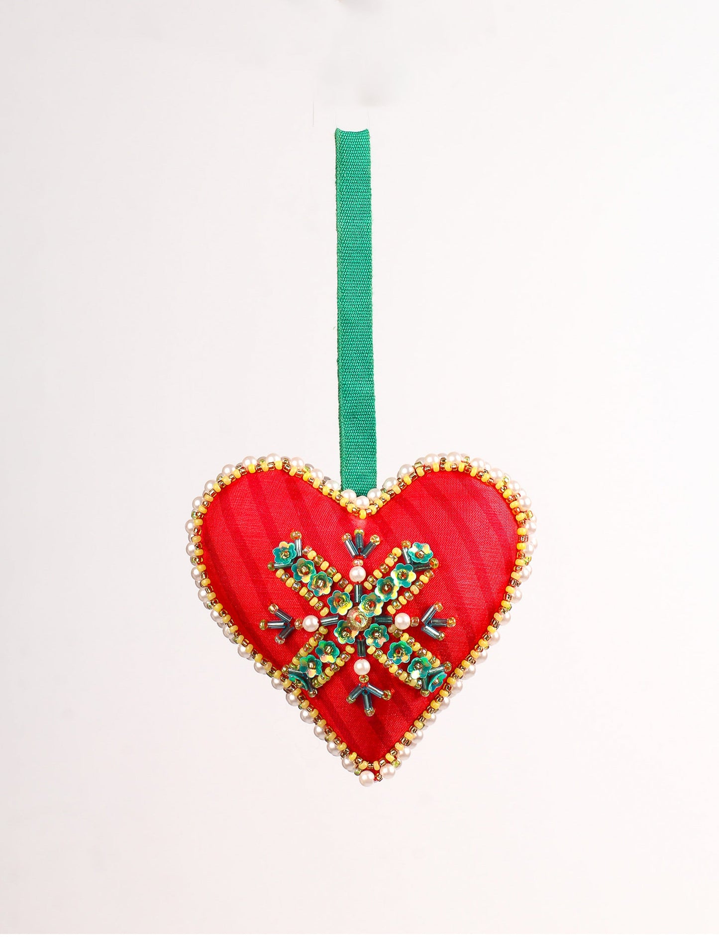 A Christmas heart ornament made from recycled sari fabric, featuring traditional Aari embroidery, representing sustainable, eco-friendly fashion. Handcrafted by artisans, this zero-waste, fair trade product symbolizes recycled material clothing and conscious clothing choices within eco-friendly and circular fashion.