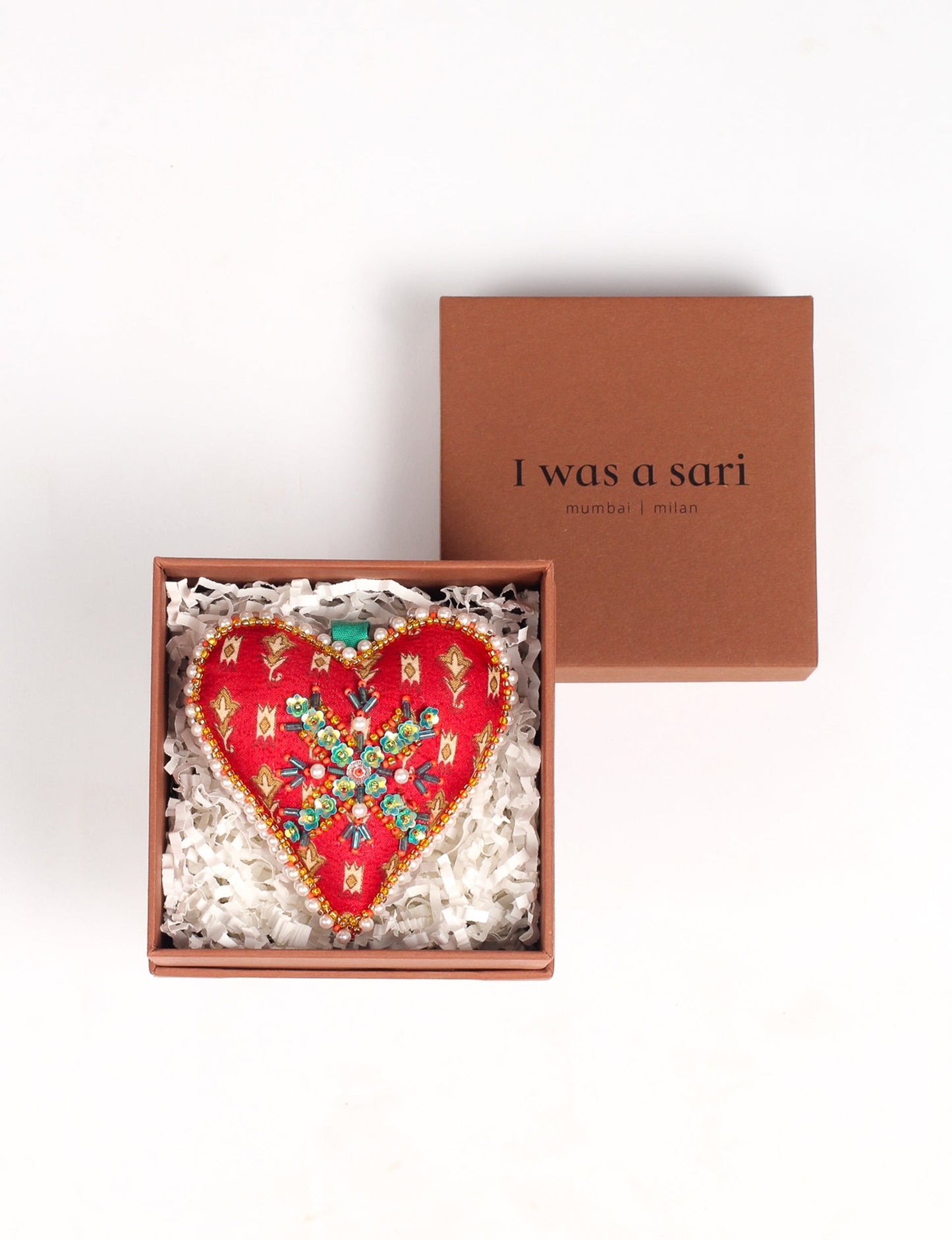 A Christmas heart ornament made from recycled sari fabric, featuring traditional Aari embroidery, representing sustainable, eco-friendly fashion. Handcrafted by artisans, this zero-waste, fair trade product symbolizes recycled material clothing and conscious clothing choices within eco-friendly and circular fashion.