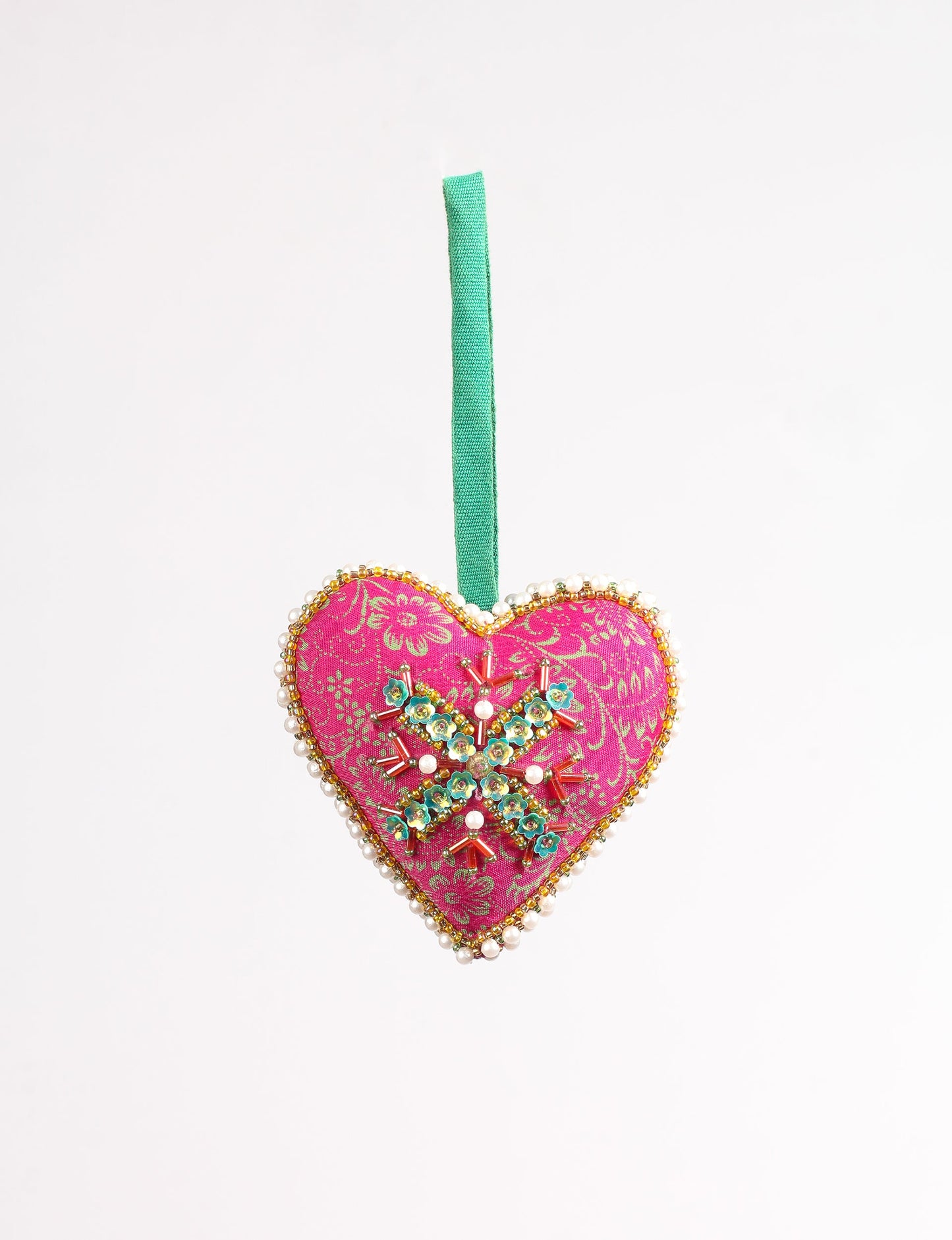 A Christmas heart ornament made from recycled sari fabric, featuring traditional Aari embroidery, representing sustainable, eco-friendly fashion. Handcrafted by artisans, this zero-waste, fair trade product symbolizes recycled material clothing and conscious clothing choices within eco-friendly and circular fashion.