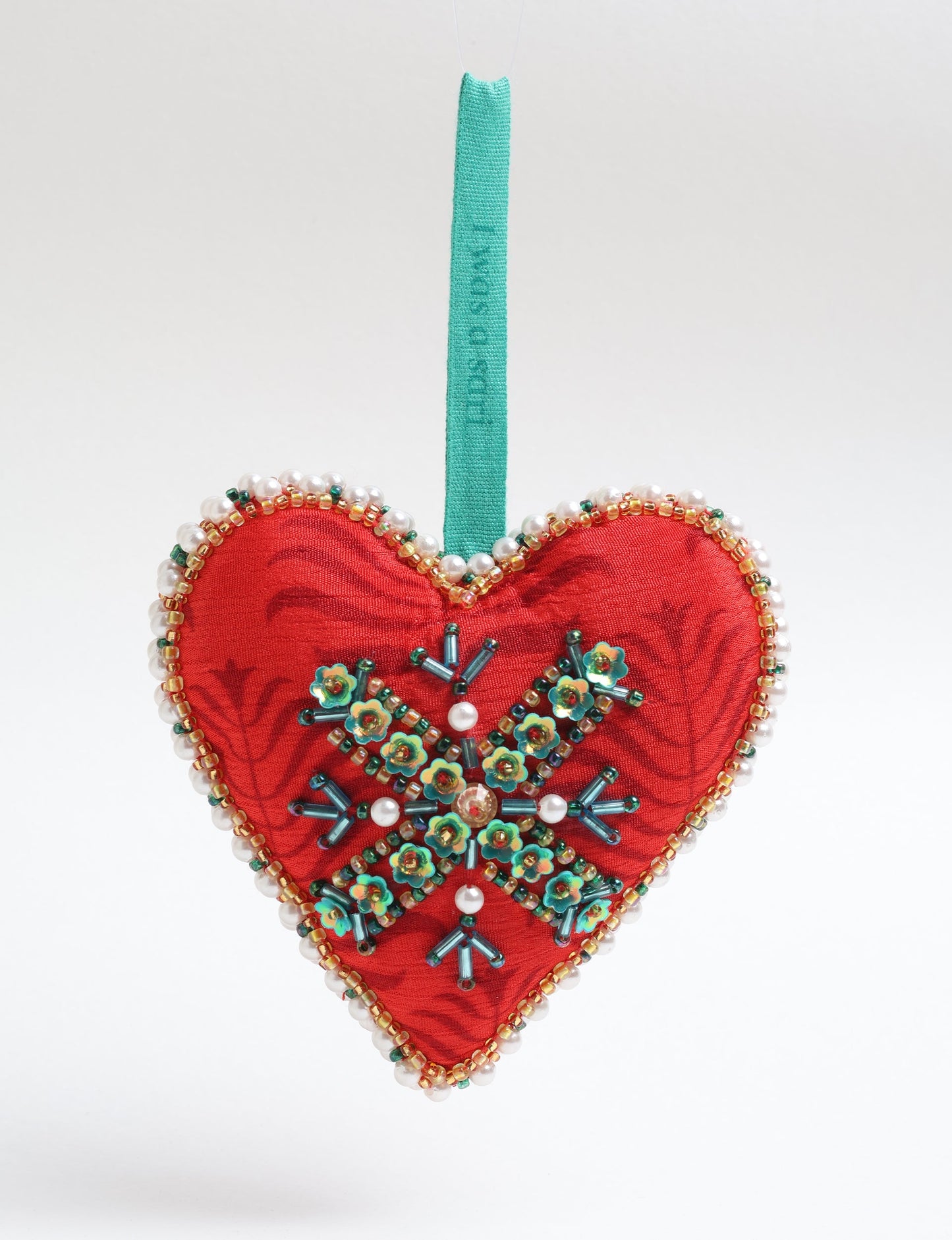 A Christmas heart ornament made from recycled sari fabric, featuring traditional Aari embroidery, representing sustainable, eco-friendly fashion. Handcrafted by artisans, this zero-waste, fair trade product symbolizes recycled material clothing and conscious clothing choices within eco-friendly and circular fashion.