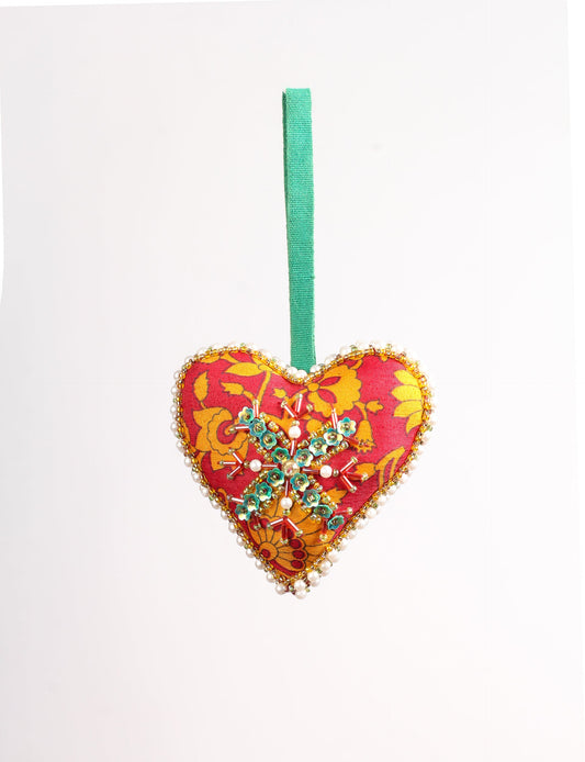 A Christmas heart ornament made from recycled sari fabric, featuring traditional Aari embroidery, representing sustainable, eco-friendly fashion. Handcrafted by artisans, this zero-waste, fair trade product symbolizes recycled material clothing and conscious clothing choices within eco-friendly and circular fashion.