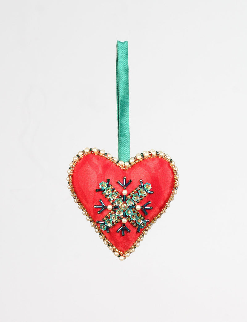 Red heart-shaped ornament with green and pearl bead snowflake design, gold bead trim, and green hanging ribbon