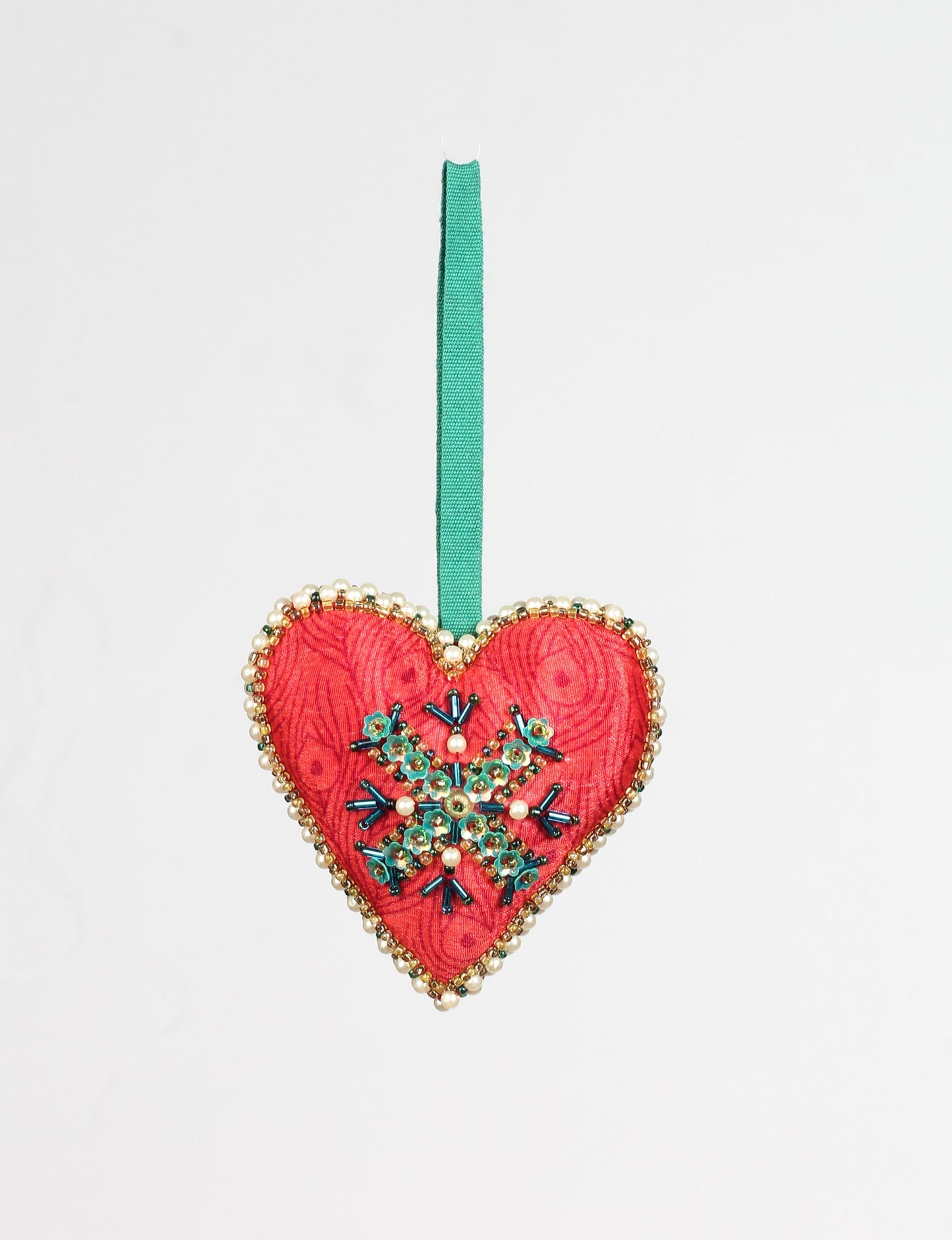 A Christmas heart ornament made from recycled sari fabric, featuring traditional Aari embroidery, representing sustainable, eco-friendly fashion. Handcrafted by artisans, this zero-waste, fair trade product symbolizes recycled material clothing and conscious clothing choices within eco-friendly and circular fashion.