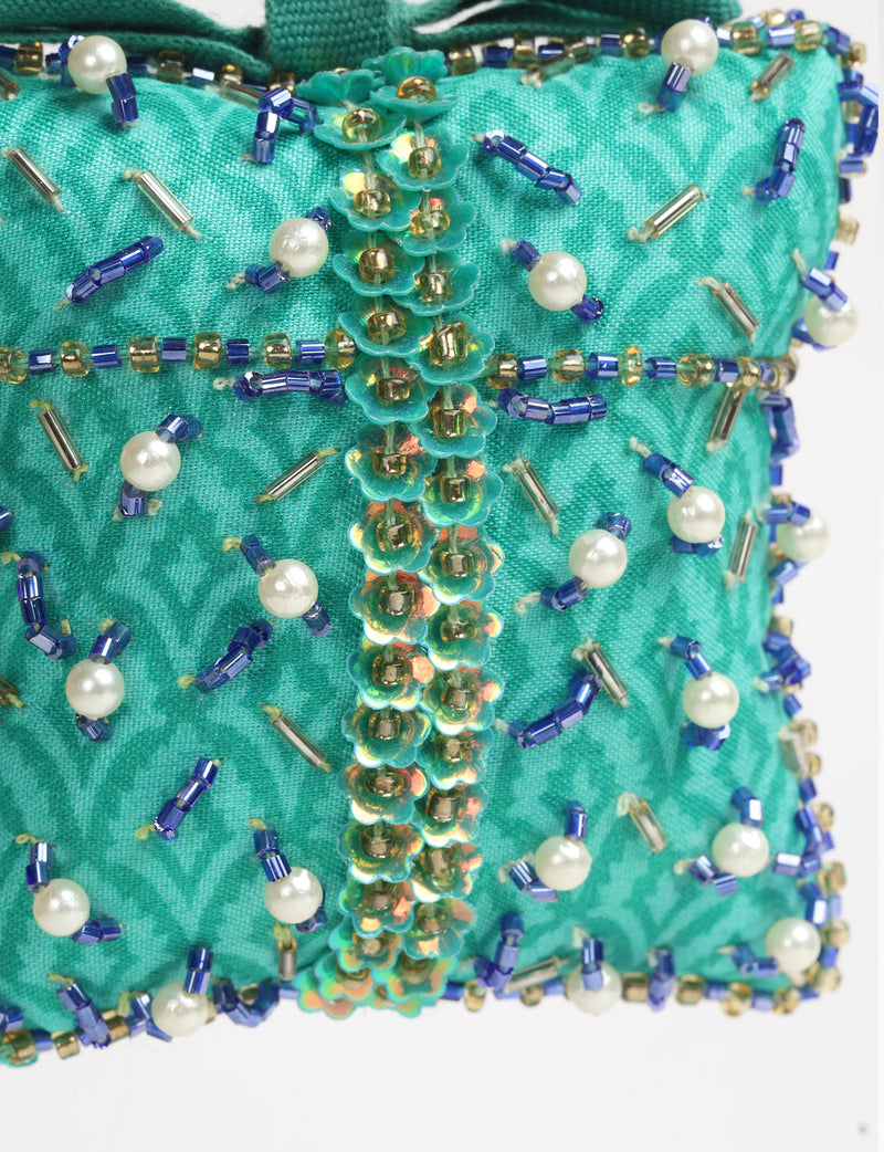 Green fabric ornament with blue and gold beads, pearl accents, and iridescent flower sequins, close-up view