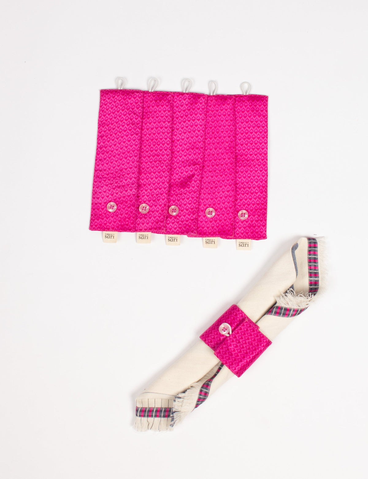 Set of five bright pink fabric napkin rings with button closures and "I was a sari" tags, shown flat and on a folded napkin