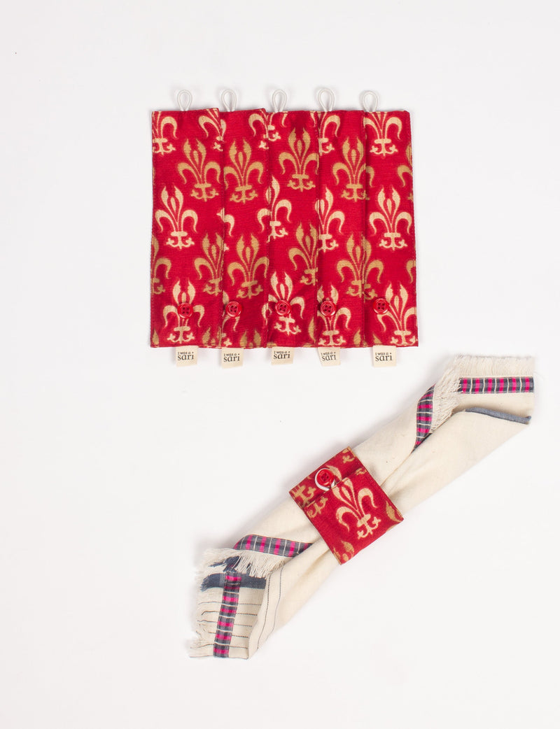 Set of six red and beige patterned fabric napkin rings with button closures, one shown wrapped around a cream napkin