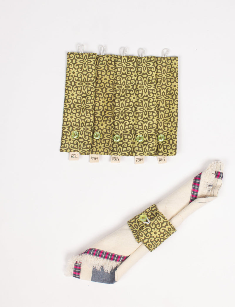 Set of six green and brown patterned fabric napkin rings with buttons and "I was a sari" tags, one holding a folded napkin