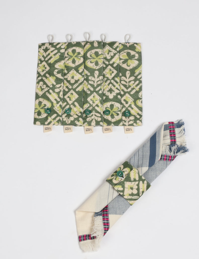 Set of six green and cream patterned fabric napkin rings with button closures and "I was a sari" tags, shown flat and on a napkin