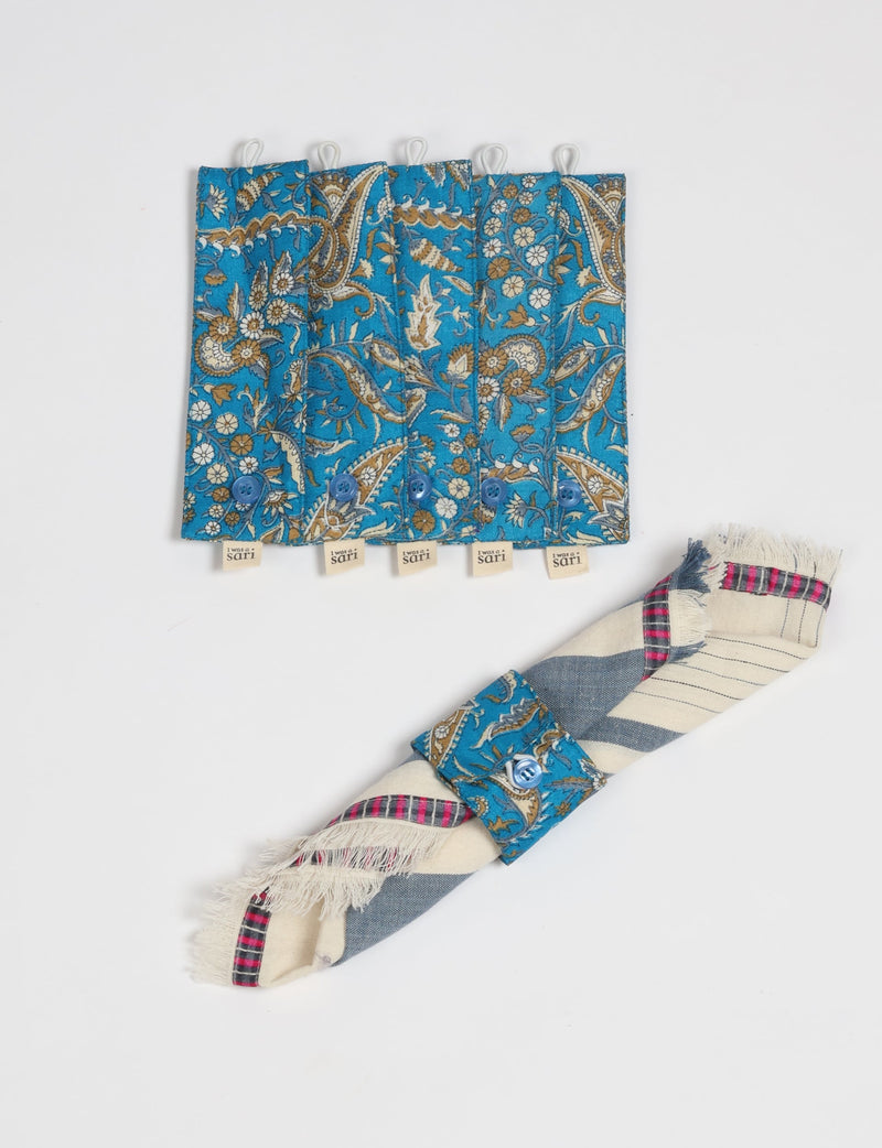Set of six blue paisley patterned fabric napkin rings with buttons and "I was a sari" tags, shown flat and on a rolled napkin