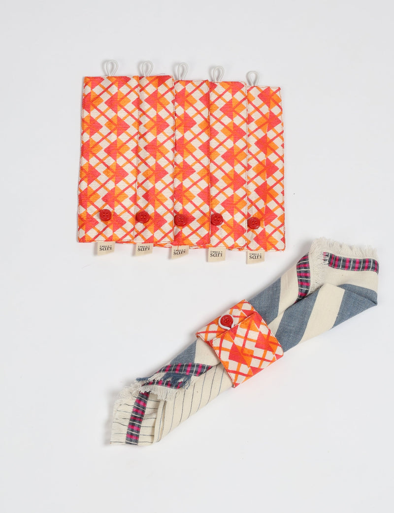 Set of six orange and red checkered fabric napkin rings with red buttons and loop closures, one shown holding a striped napkin