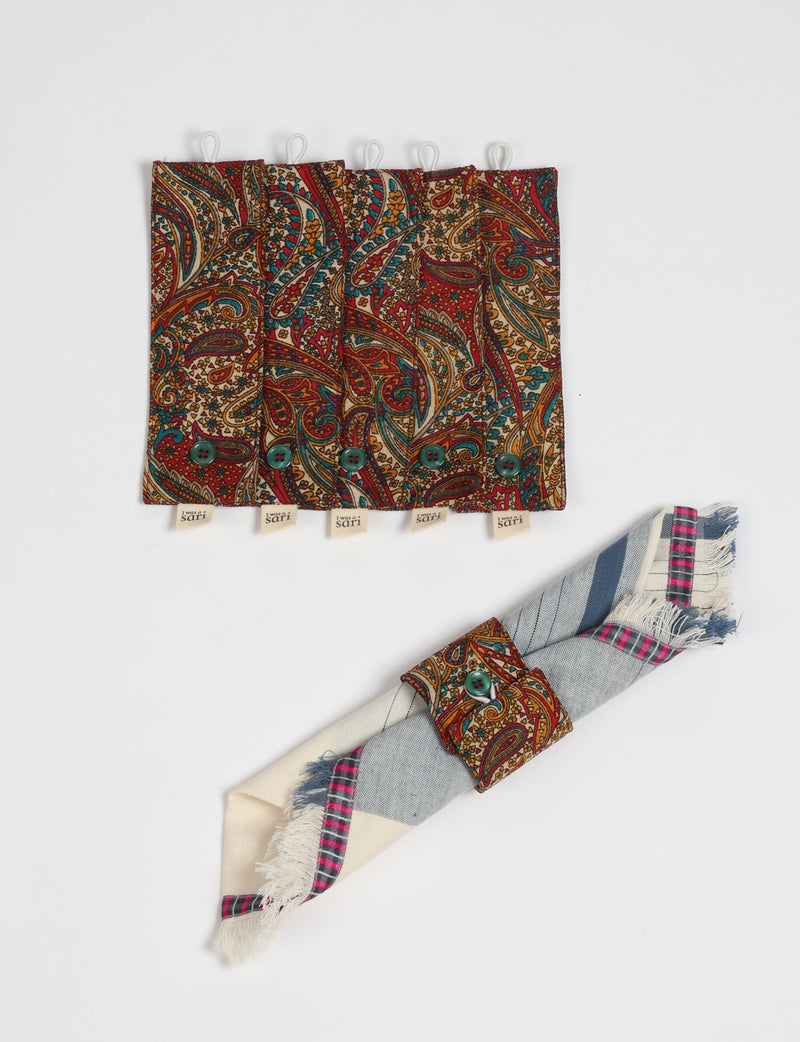 Set of six paisley patterned fabric napkin rings with green buttons and "I was a sari" tags, shown flat and on a rolled napkin