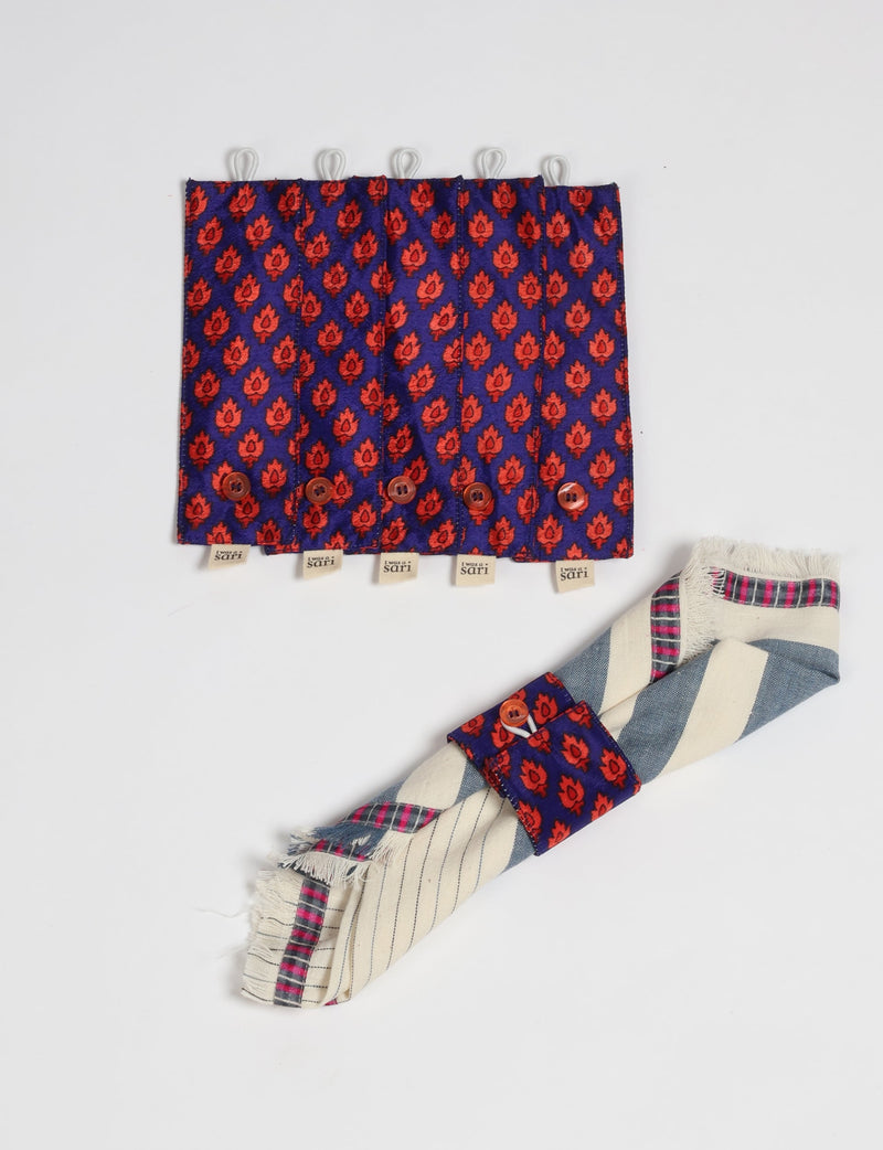 Set of 6 blue and red patterned fabric napkin rings with buttons, shown flat and one wrapped around a striped napkin