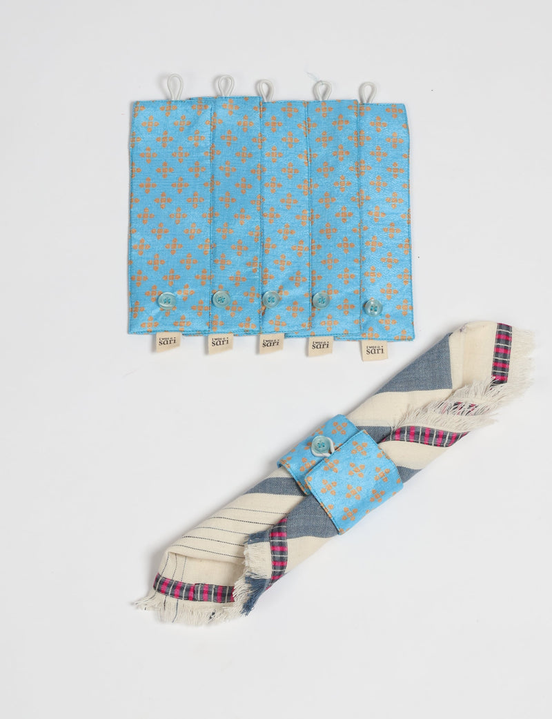 Set of six blue fabric napkin rings with orange floral pattern and button closures, one shown holding a folded napkin