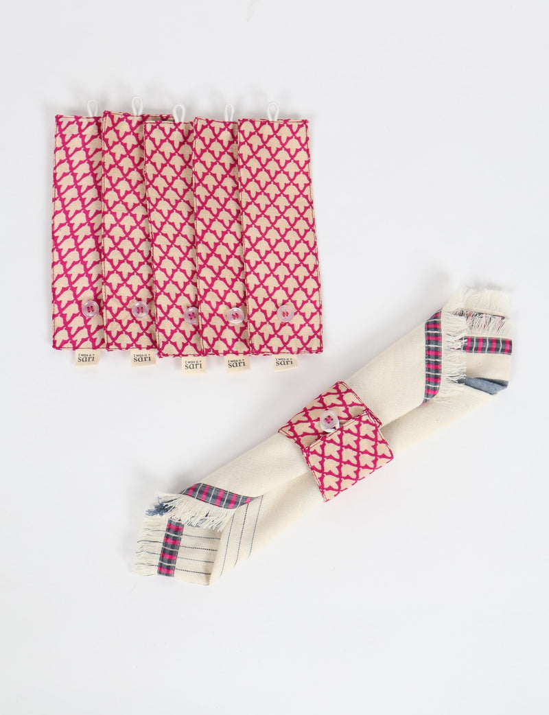 Set of six pink and beige napkin rings with micro geometric pattern and button closure, shown flat and on a folded napkin