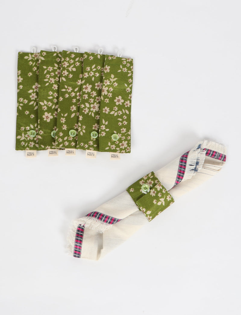Set of six green floral fabric napkin rings with small buttons and "I was a sari" tags, one holding a folded napkin
