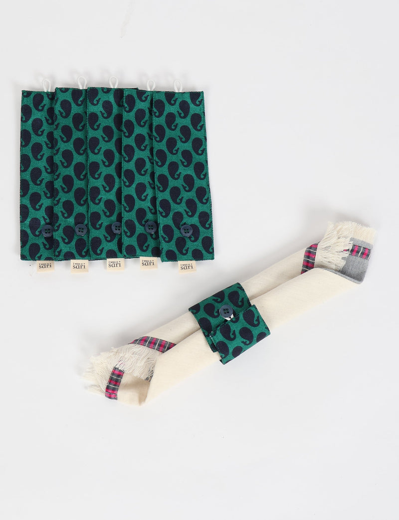 Set of six green fabric napkin rings with dark paisley pattern and black button closures, one shown on a rolled beige napkin