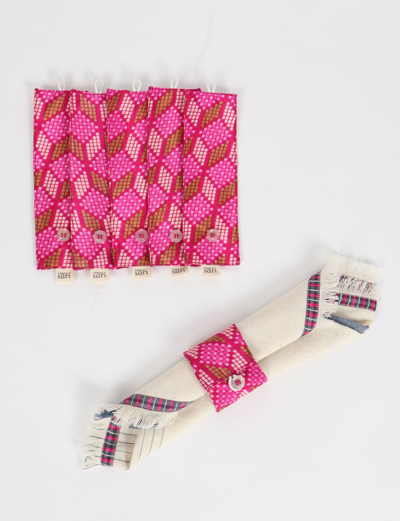Set of six pink geometric patterned fabric napkin rings with button closures, shown flat and one wrapped around a napkin