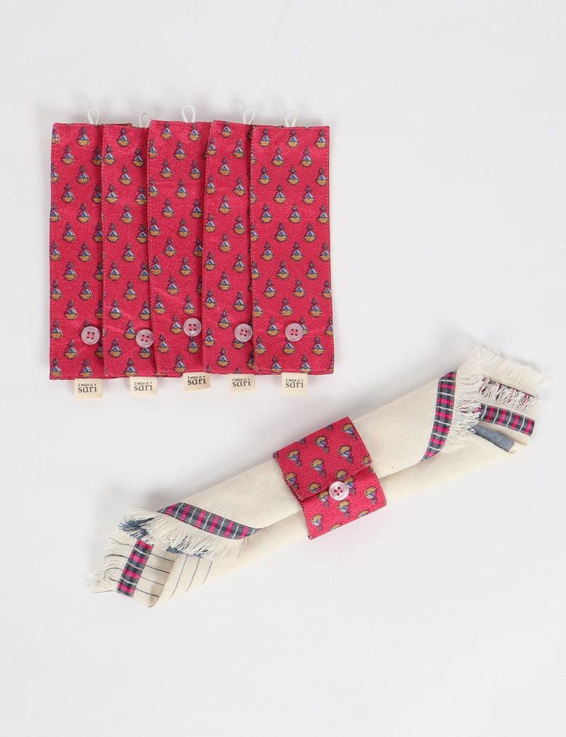 Set of six pink fabric napkin rings with micro pattern and button closure, shown flat and holding a folded napkin