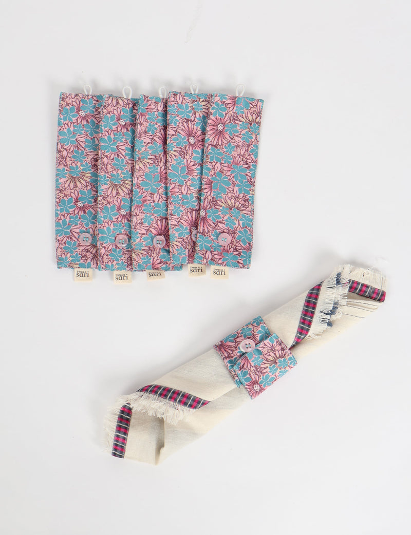 Set of six blue floral fabric napkin rings with button closures and "I was a sari" tags, shown flat and on a rolled napkin