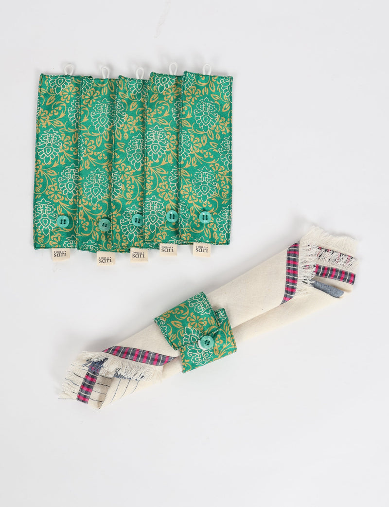 Set of six green tropical patterned fabric napkin rings with buttons and "I was a sari" tags, shown flat and on a rolled napkin