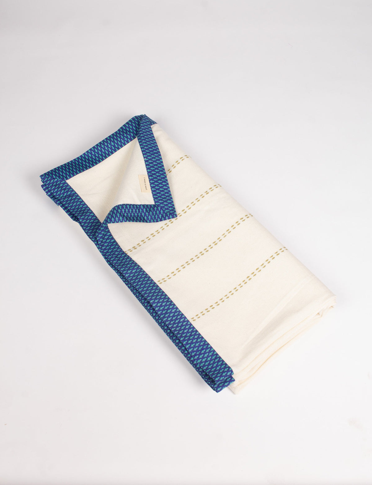 Folded cotton sofa throw in off-white with blue abstract patterned broad sari edging and stitched horizontal lines
