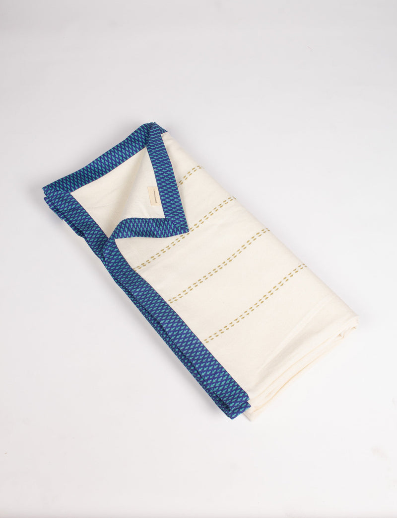 Folded cotton sofa throw in off-white with blue abstract patterned broad sari edging and stitched horizontal lines