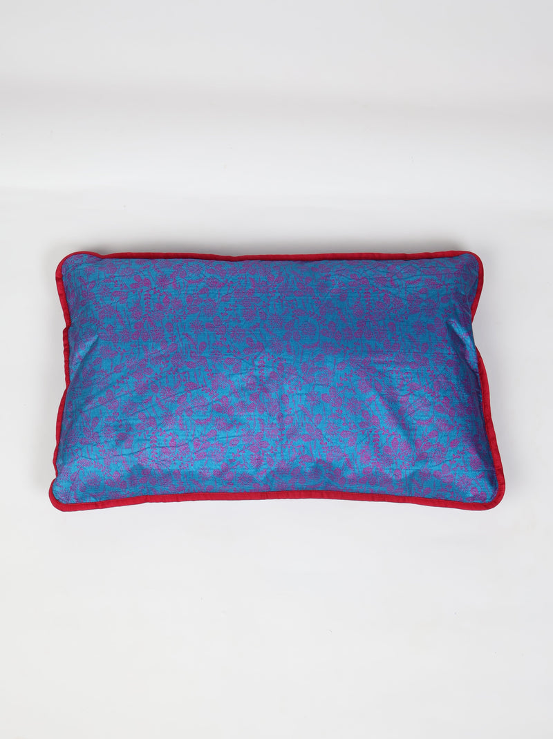 Rectangular lumbar cushion cover in blue cotton with purple floral print and red piping edge, flat lay view