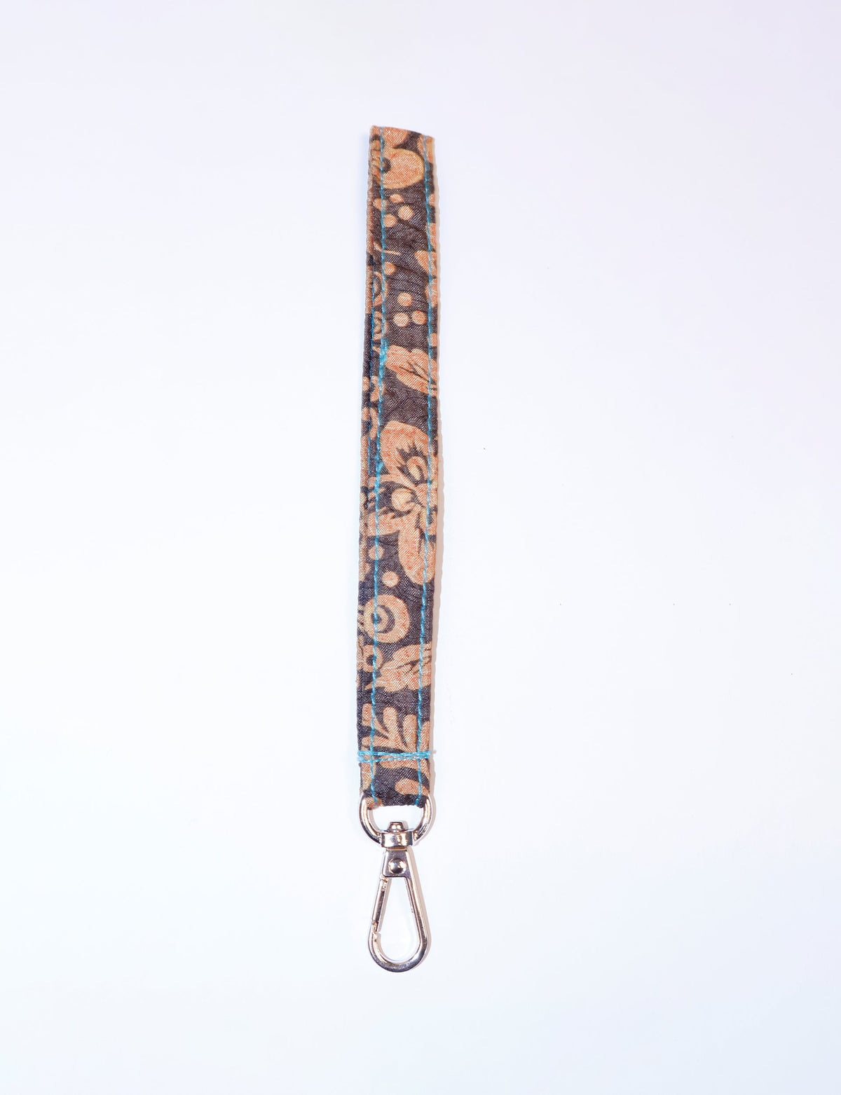 Brown tropical patterned fabric keychain lanyard with blue stitching and silver metal clasp, flat lay on white background