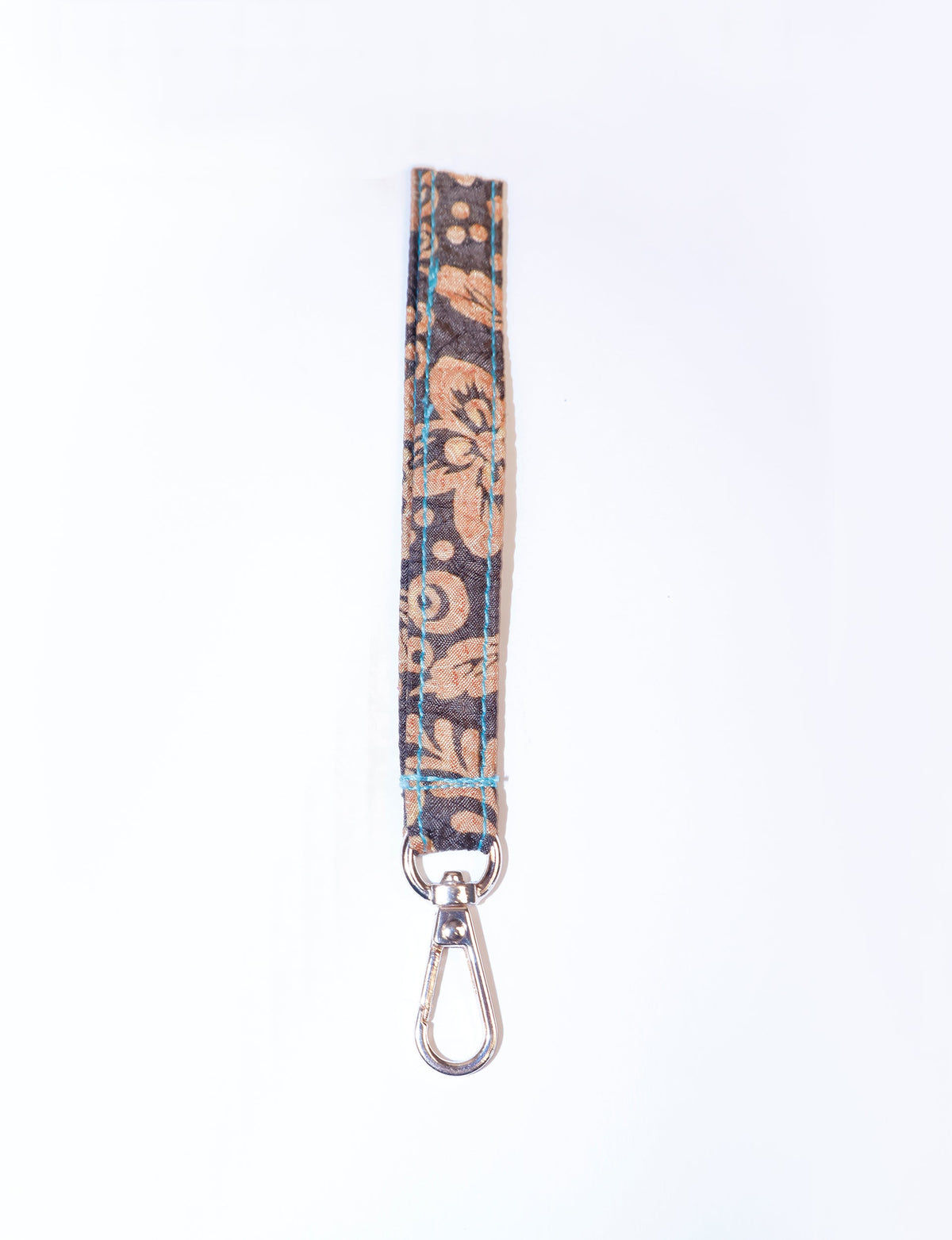 Brown tropical patterned fabric keychain lanyard with blue stitching and silver metal clasp, flat lay on white background