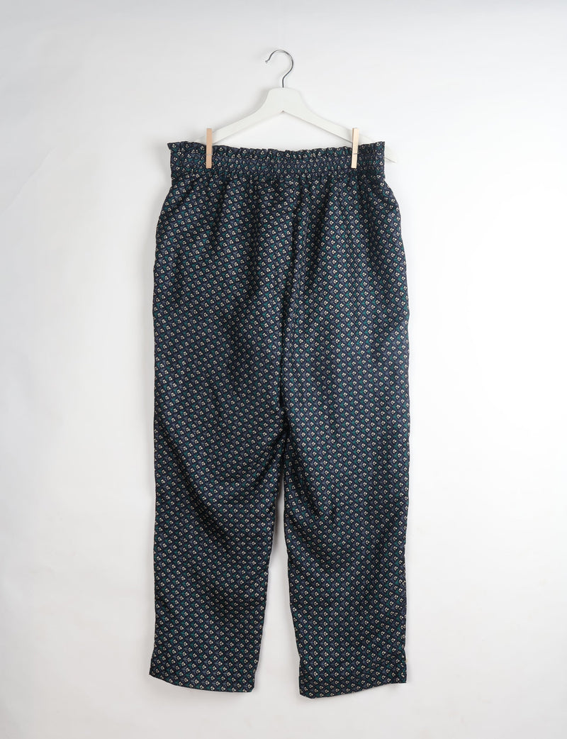Blue paperbag high-waisted pull-on pants with a small floral micro design, hanging on a white hanger against a white background