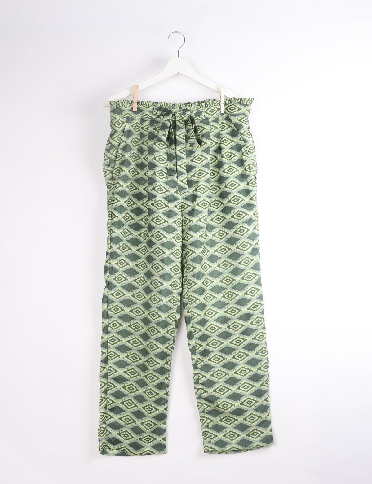 Green geometric patterned paperbag high-waisted pull-on pants hanging on white hanger, front view