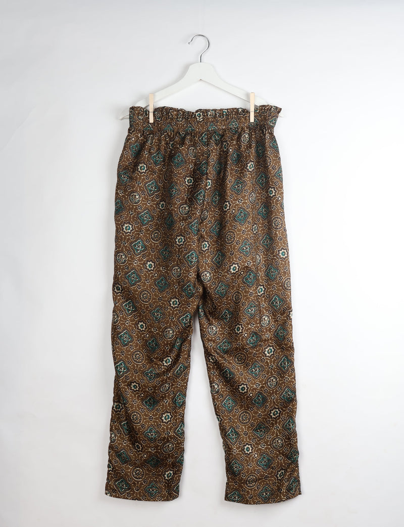 Green and brown paperbag high-waisted pull-on pants with Indian ethnic print, hanging on white hanger, front view