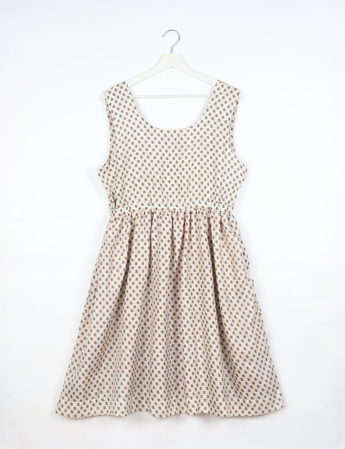 White fit and flare dress with small brown floral print, sleeveless, scoop neckline, hanging on white hanger, front view
